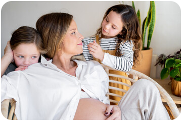 Femme enceinte assise en pleine réflexion, entourée de ses deux fillettes